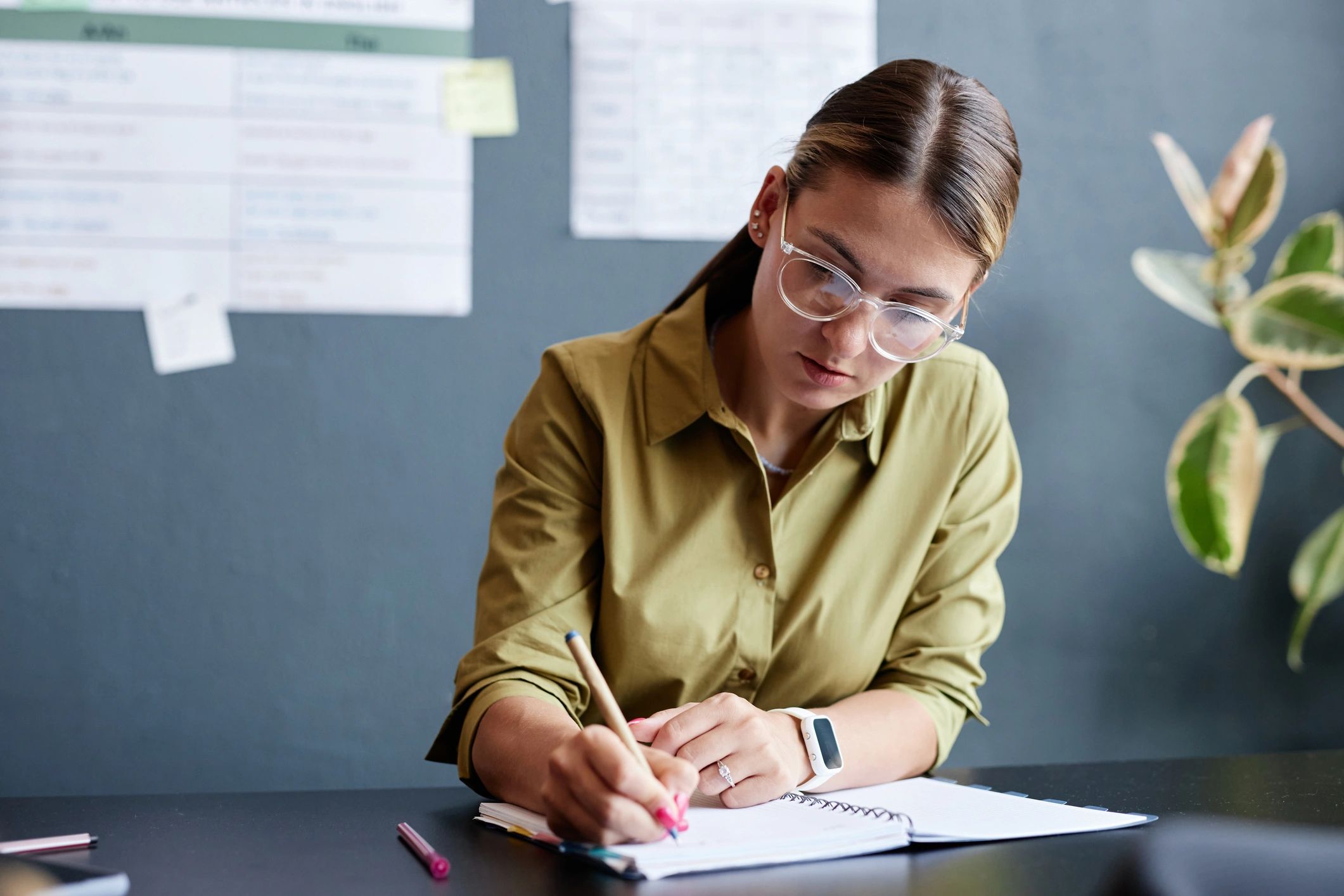 Instructor writing in a notebook at a classroom desk